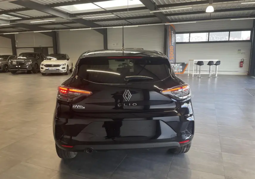 Vue arrière d'une Renault Clio 1.5 Blue dCi noire étoile avec feux LED allumés en intérieur showroom.