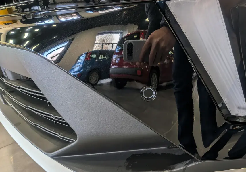 Détail du pare-chocs avant noir étoilé du Renault Symbioz E-Tech 160 ch, avec capteur de stationnement visible.