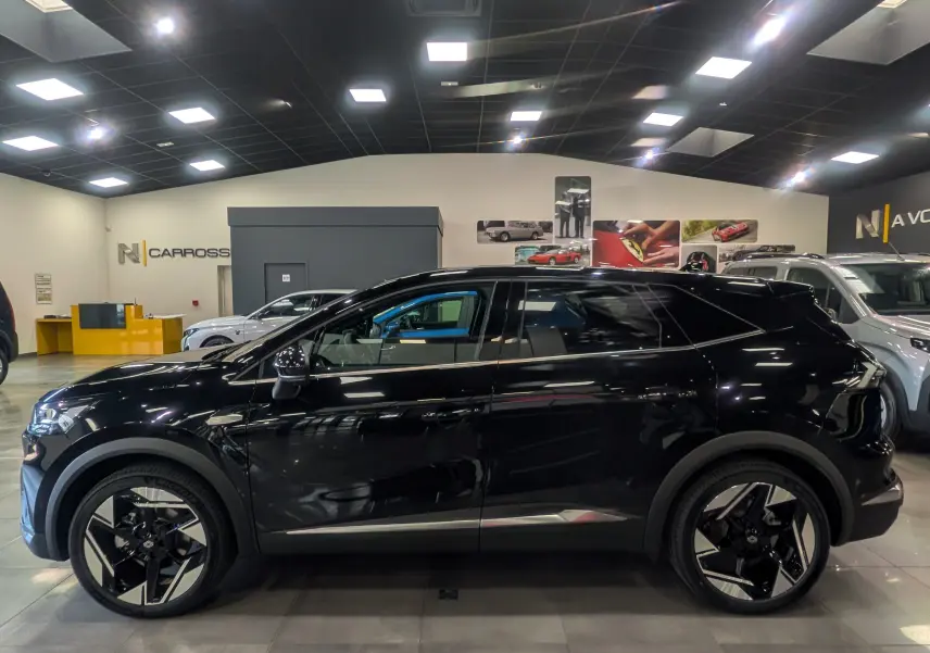 Vue de profil côté gauche d'un Renault SYMBIOZ E-Tech full hybrid noir étoilé, avec jantes design bicolores en showroom.