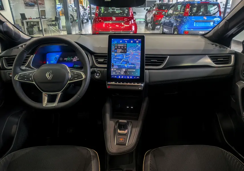 Intérieur de la Renault SYMBIOZ E-Tech 160 ch, vue frontale du tableau de bord avec écran tactile vertical et volant multifonction.