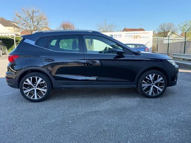 Vue de profil côté gauche du SEAT Arona noir avec toit gris, jantes alliage 18 pouces et vitres arrière surteintées.