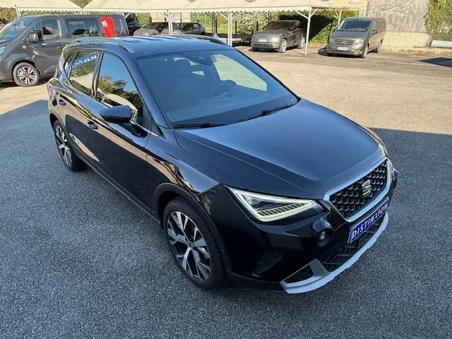 SEAT Arona noir avec toit gris, vue 3/4 avant droit, jantes alliage 18 pouces et phares LED allumés.