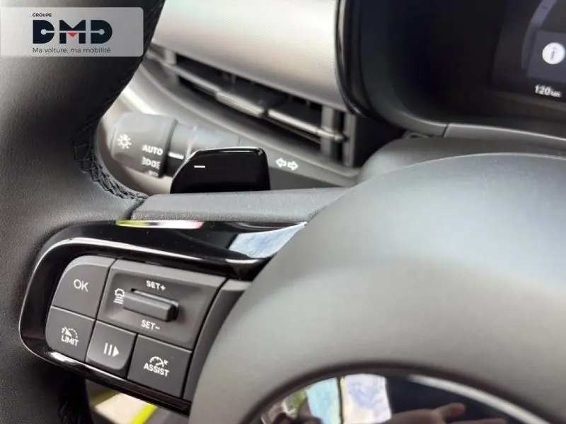 Gros plan sur les commandes au volant noir et gris de la FIAT 600 Hybrid Turbo, avec palettes de changement de vitesse.