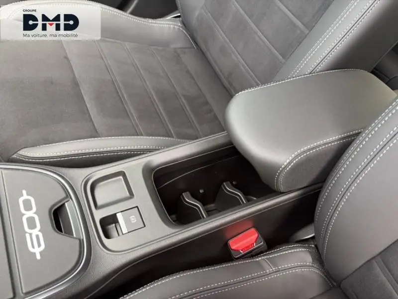 Gros plan intérieur sur l'accoudoir central et les sièges noirs avec surpiqûres blanches de la FIAT 600 hybride 2026.