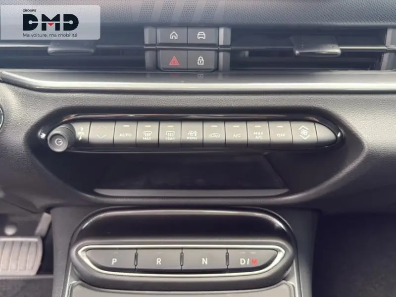 Vue rapprochée de la console centrale noire du Fiat 600 Hybrid avec commandes climatisation et boîte auto à boutons.