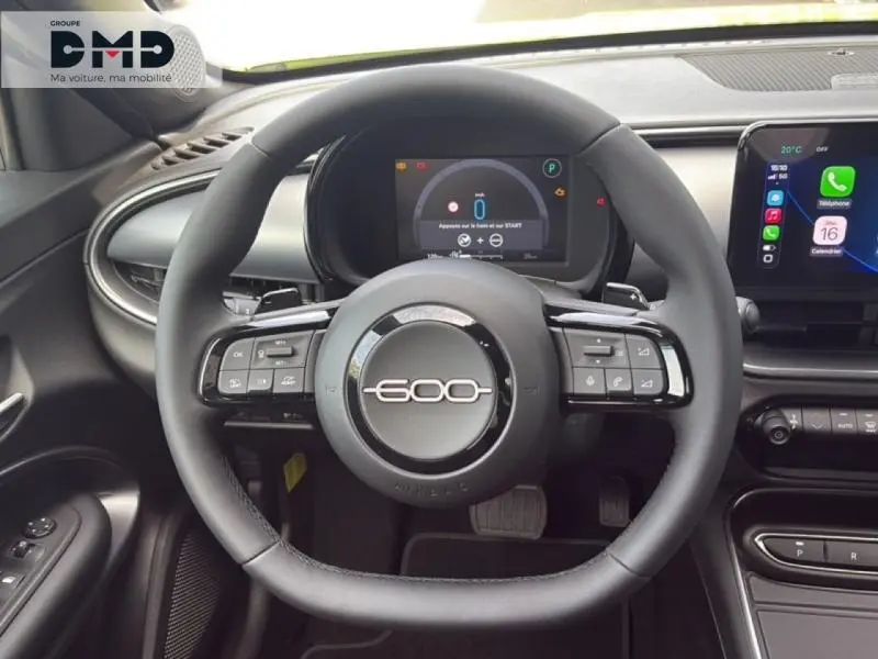 Vue intérieure centrée sur le volant noir de la Fiat 600 avec affichage numérique et écran tactile multimédia.
