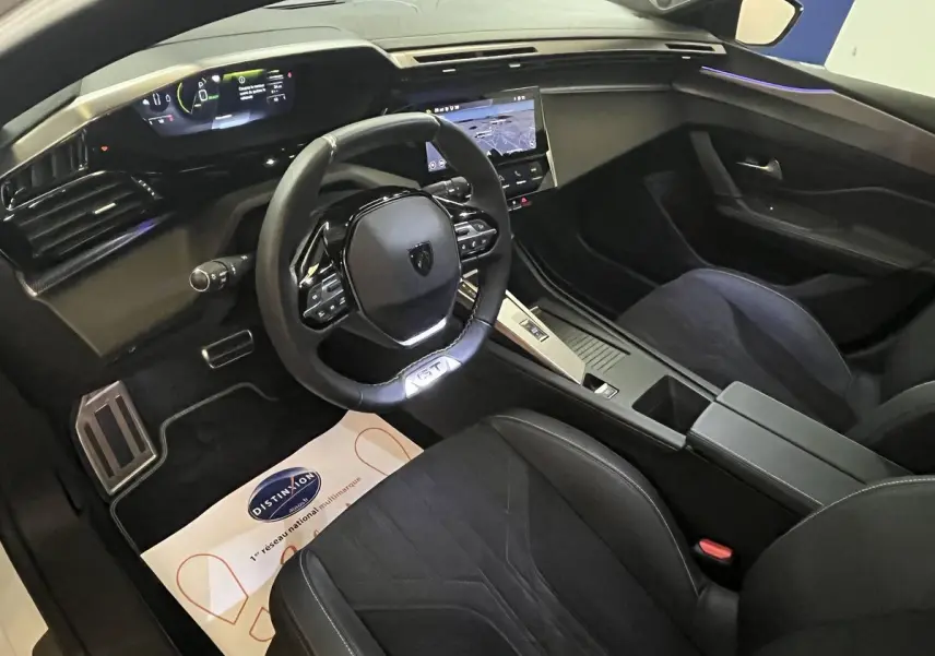 Intérieur noir de la Peugeot 308 GT PHEV 2022 vu côté conducteur, tableau de bord numérique et écran tactile central visibles.