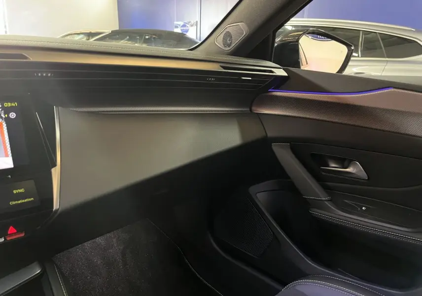 Intérieur côté passager de la Peugeot 308 GT PHEV 180 blanc nacré avec éclairage d'ambiance bleu et tableau de bord moderne.