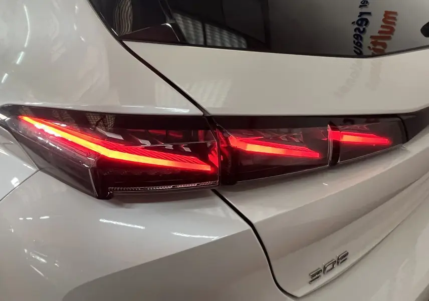 Gros plan sur le feu arrière droit rouge vif d'une Peugeot 308 GT PHEV blanc nacré, vue arrière détaillée.
