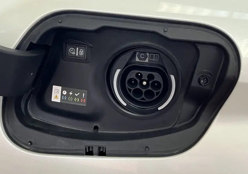 Détail de la trappe de recharge hybride blanche nacrée d'une Peugeot 308 GT PHEV 180 vue de près.
