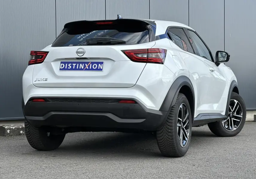 Vue 3/4 arrière droit du Nissan Juke blanc nacré 2025 avec jantes alliage et feux LED distinctifs.