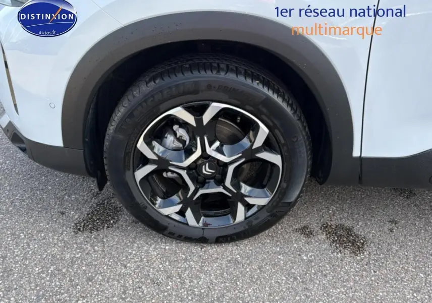 Gros plan sur la roue avant gauche d’un Citroën C5 Aircross blanc avec jante alu noire et argentée.