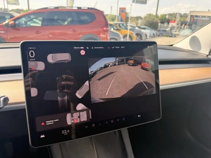Écran central tactile du Tesla Model 3 noir 2022 montrant la caméra de recul et l'interface de conduite.