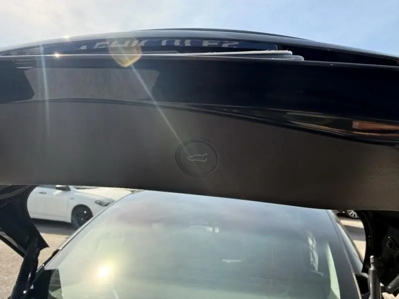 Vue depuis l'intérieur du coffre ouvert d'une Tesla Model 3 noire 2022, avec bouton de fermeture visible sous le hayon.