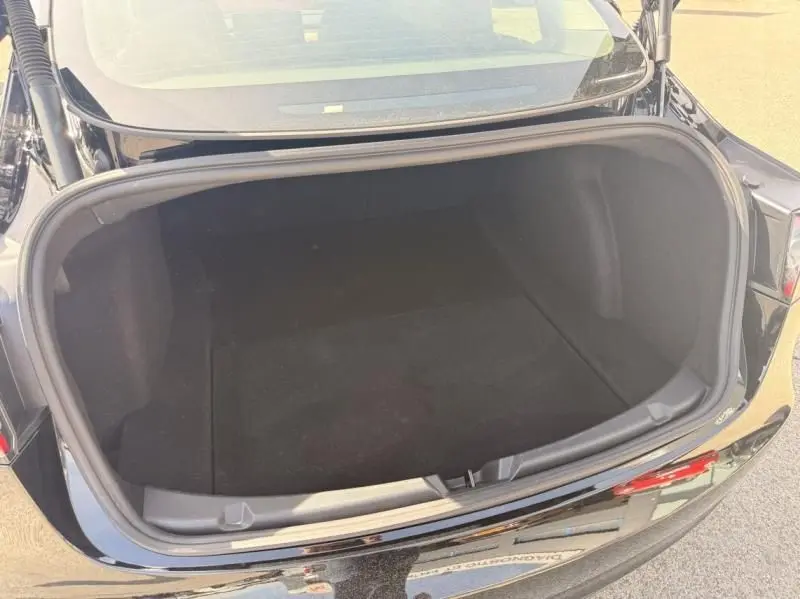 Coffre ouvert vu de l'arrière d'une Tesla Model 3 Standard RWD Plus noire de 2022, montrant un espace de rangement vide.