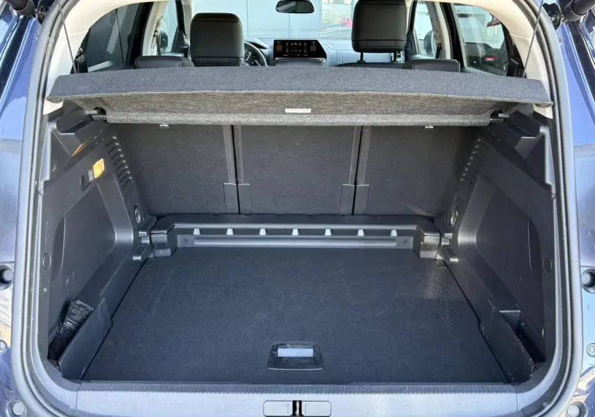 Coffre ouvert vu de l'arrière d'un Citroën C5 Aircross Hybrid bleu Eclipse, avec cache-bagages et sièges arrière visibles.