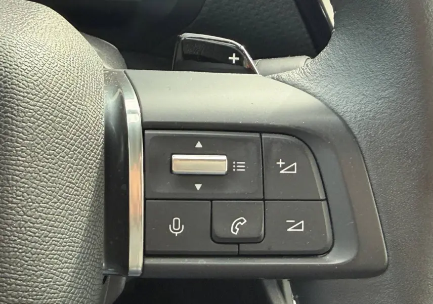 Gros plan sur les commandes vocales et téléphoniques au volant cuir noir de la Citroën C4 hybride 2025.