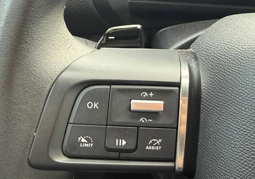 Gros plan sur les commandes au volant gauche de la Citroën C4 noire, avec boutons de régulateur et limiteur de vitesse.