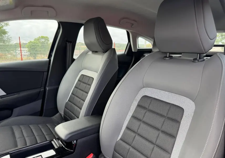 Gros plan sur les sièges avant gris et noirs avec accoudoir central de la Citroën C4 1.2 Hybride 2025.