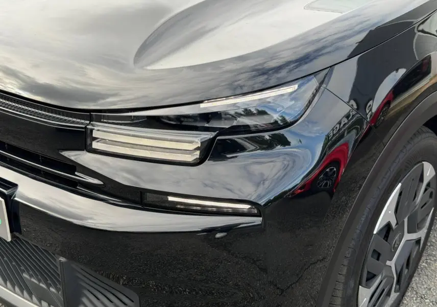 Gros plan sur l'avant droit noir Perla Nera d'une Citroën C4 2025, avec phares LED et jante alu visible.