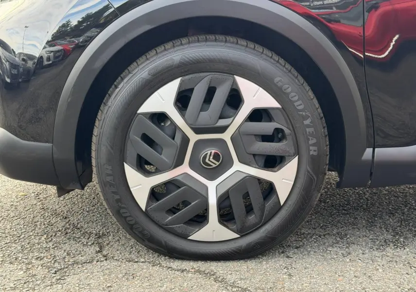 Gros plan sur la roue avant droite noire Perla Nera d'une Citroën C4 1.2 Hybride avec jante alu bicolore.