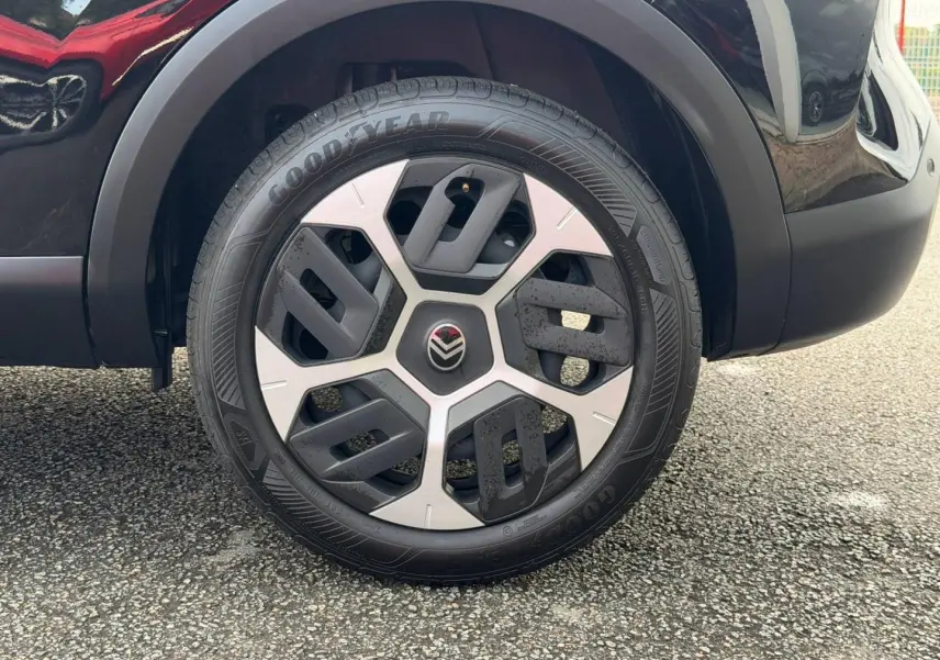 Gros plan sur la roue avant droite noire Perla Nera du Citroën C4 1.2 Hybride 145ch avec jante alu distinctive.