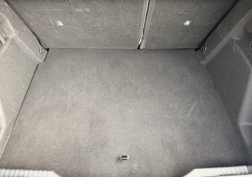 Coffre spacieux vu de dessus, revêtement gris foncé, banquette arrière rabattable visible en partie.