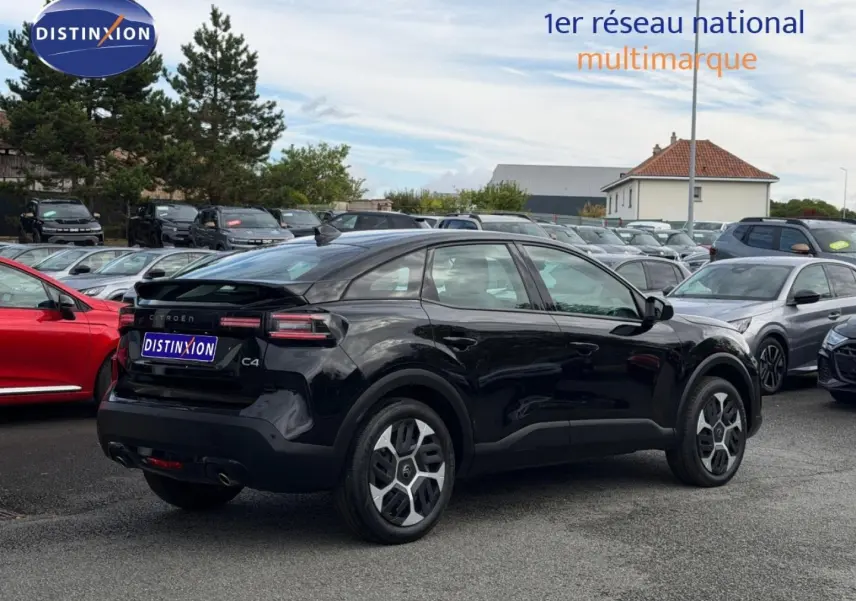 Vue 3/4 arrière droite d'une Citroën C4 noire Perla Nera avec jantes alu et feux arrière LED dans un parking.