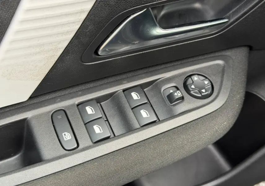 Gros plan sur les commandes de lève-vitres et rétroviseurs côté conducteur d'une Citroën C4 noire.