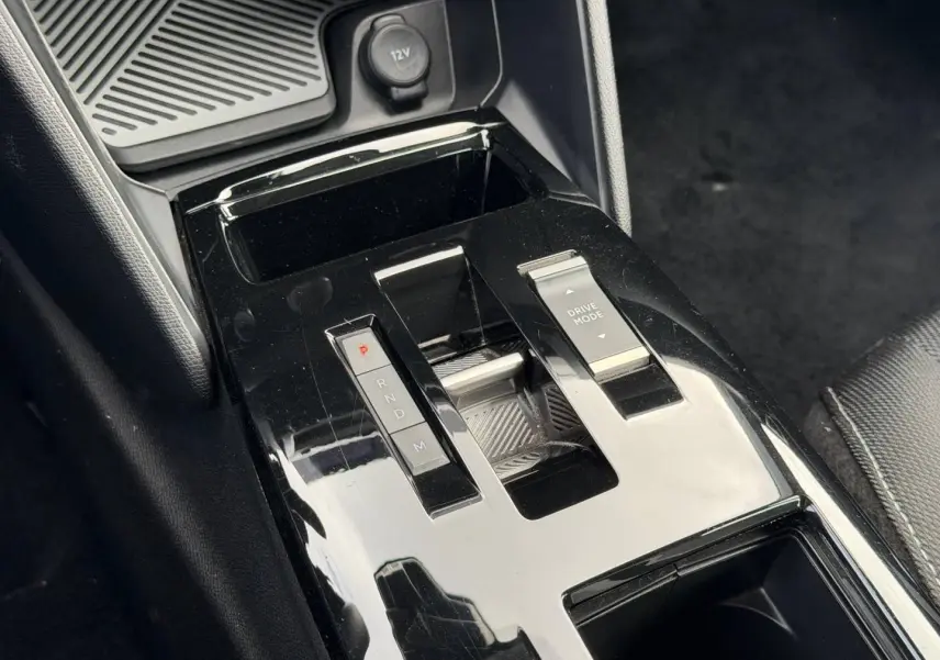 Gros plan sur la console centrale noire brillante avec levier de vitesses automatique et bouton Drive Mode du Citroën C4 hybride.
