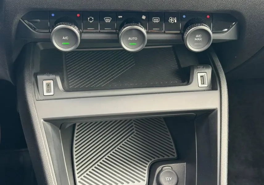 Vue rapprochée de la console centrale de la Citroën C4 1.2 Hybride 145ch, avec commandes climatisation et ports USB.