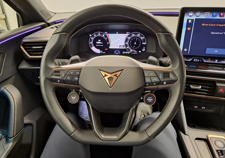 Vue centrée sur le volant cuir perforé de la CUPRA Leon 2025 avec logo cuivré et tableau de bord numérique.