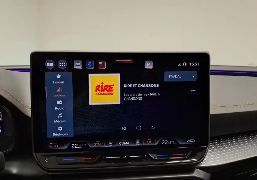 Écran tactile central du tableau de bord de la CUPRA Leon 2025, affichant la radio FM/DAB avec ambiance intérieure moderne.