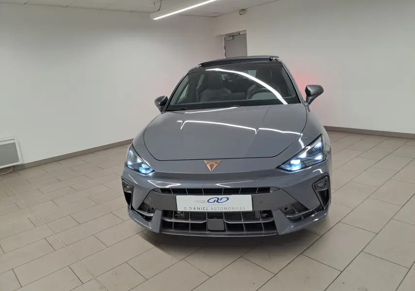 Vue avant d'une CUPRA Leon 1.5 eTSI 150 DSG7 en gris Graphène avec toit ouvrant panoramique et éclairage LED allumé.