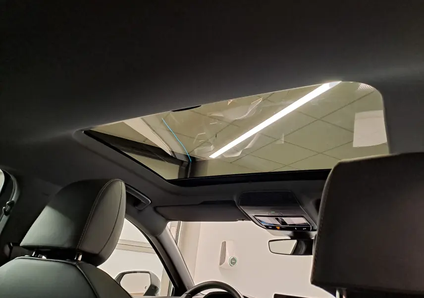 Vue intérieure du toit ouvrant panoramique du CUPRA Leon 2025, avec sièges avant en cuir et console de toit visible.