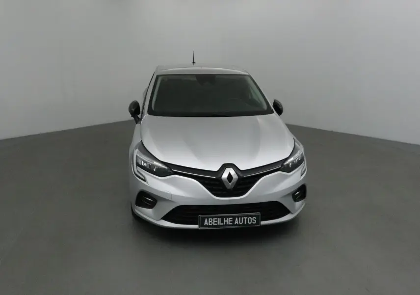 Vue frontale d'une Renault Clio V gris platine 2021 avec calandre noire et phares LED allumés.