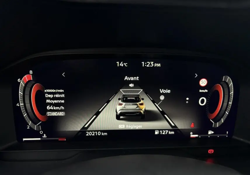 Affichage numérique du tableau de bord du Nissan Juke blanc nacré, montrant la vitesse moyenne et l'aide au maintien de voie.