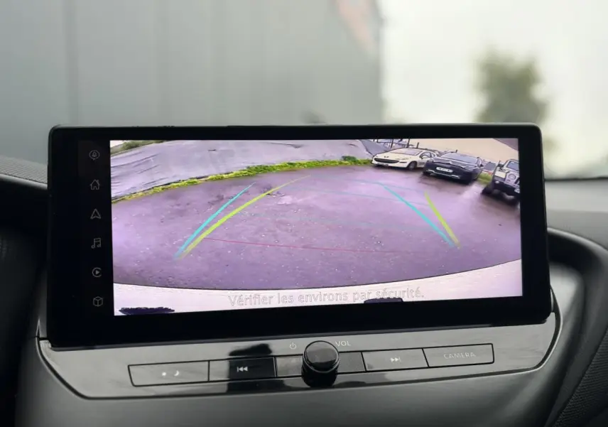 Écran tactile du Nissan Juke 2025 montrant la caméra de recul avec guidage dynamique en intérieur noir.