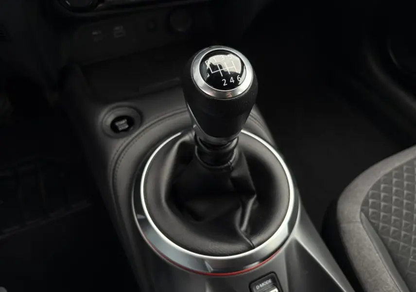Gros plan sur le levier de vitesses manuel entouré de cuir noir dans l'habitacle du Nissan Juke 2025.