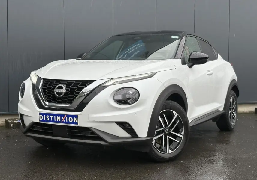 Nissan Juke blanc nacré en 3/4 avant droit, avec toit noir et jantes alliage 17 pouces distinctives.