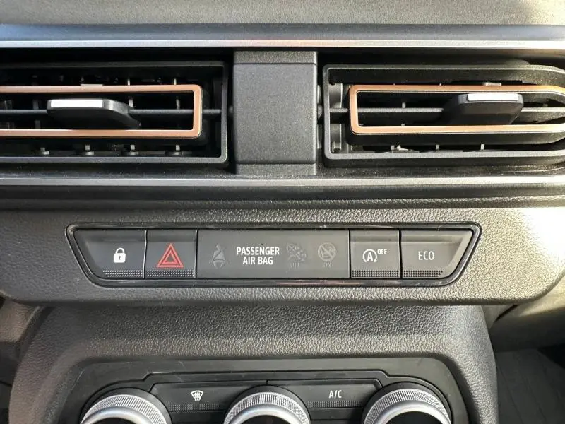 Détail du tableau de bord de la Dacia Sandero 2025, montrant les aérateurs et les boutons de sécurité et mode ECO.