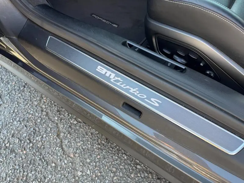 Gros plan sur la plaque de seuil de porte côté gauche de la Porsche 911 Turbo S 2020, intérieur cuir noir.