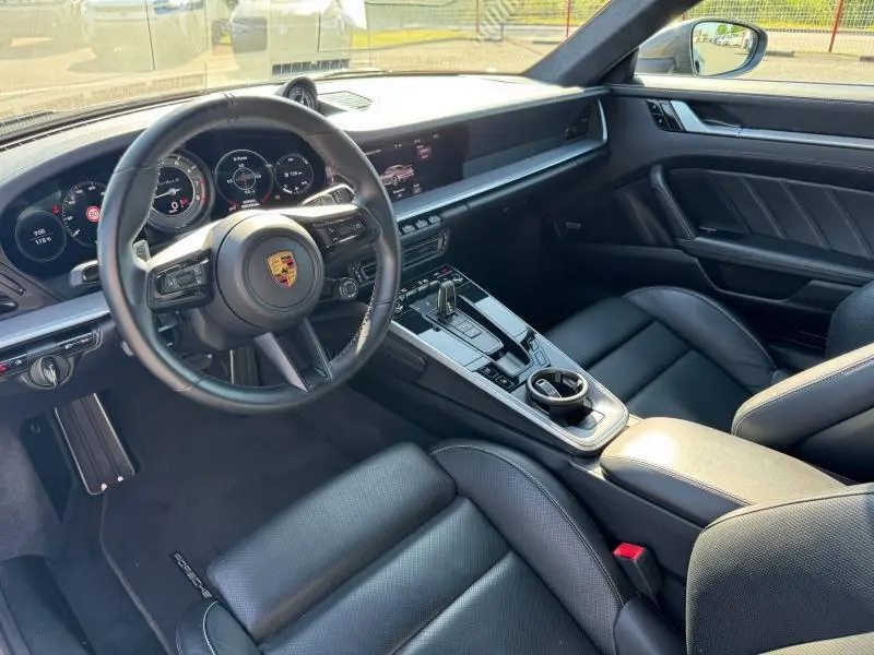 Intérieur noir de Porsche 911 Turbo S 2020 vu côté conducteur, volant cuir multifonction et console centrale moderne.