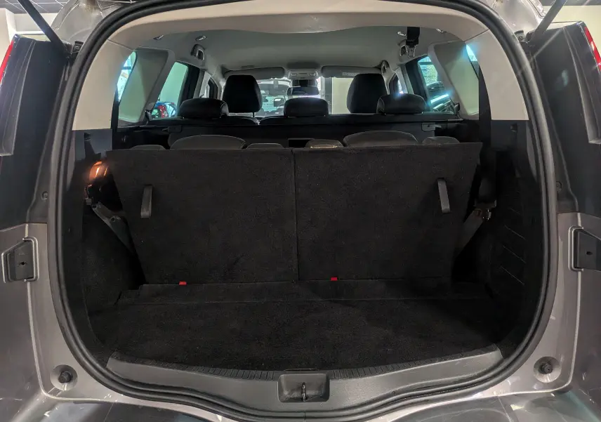 Coffre ouvert vu de l'arrière d'un Renault Grand Scénic IV gris Cassiopé avec banquette arrière relevée et intérieur sombre.