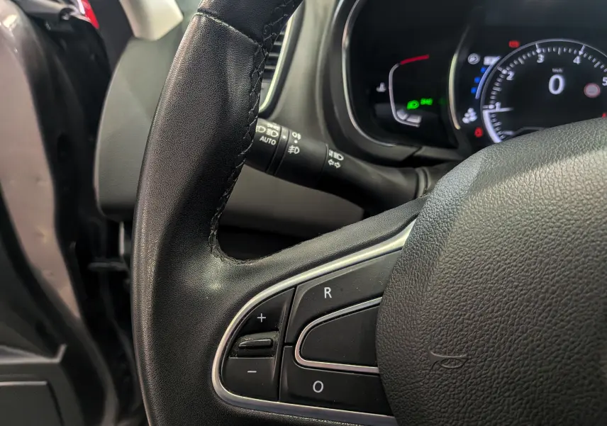Gros plan sur le volant noir du Renault Grand Scenic IV 2023, montrant les commandes de régulateur de vitesse.