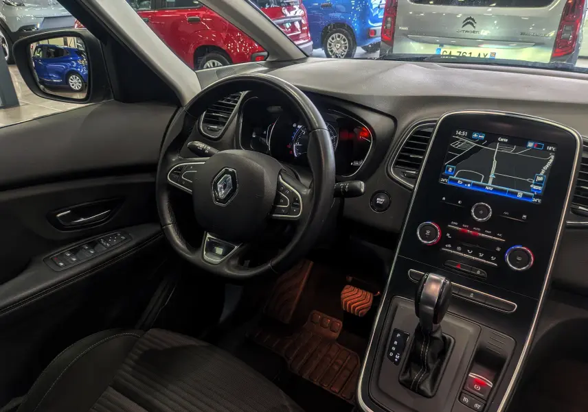 Vue intérieure côté conducteur du Renault Grand Scenic IV gris Cassiopé, avec volant multifonction et écran tactile central affichant la navigation.