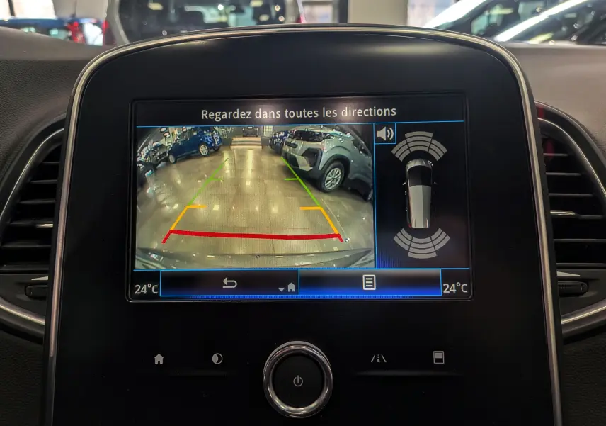 Vue intérieure du tableau de bord du Renault Grand Scenic IV avec écran de caméra de recul affichant un parking intérieur.