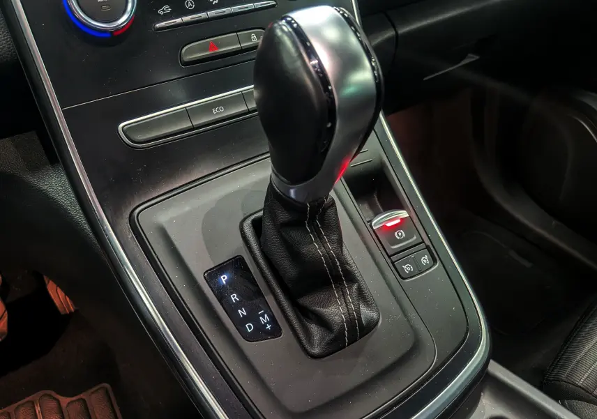 Gros plan sur le levier de vitesses automatique noir et argenté du Renault Grand Scenic IV TCe 140, intérieur sombre.
