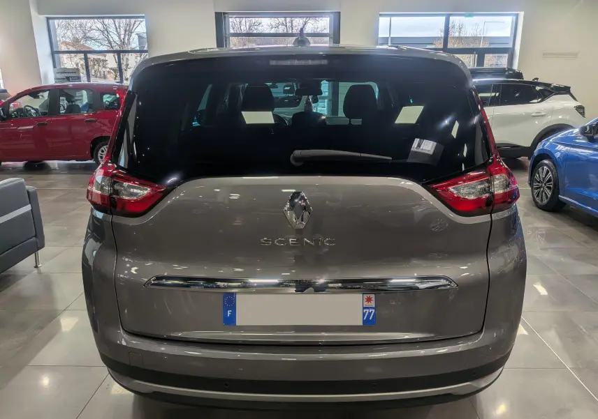 Vue arrière du Renault Grand Scénic IV gris Cassiopé 2023 en intérieur, avec logo et feux distinctifs visibles.