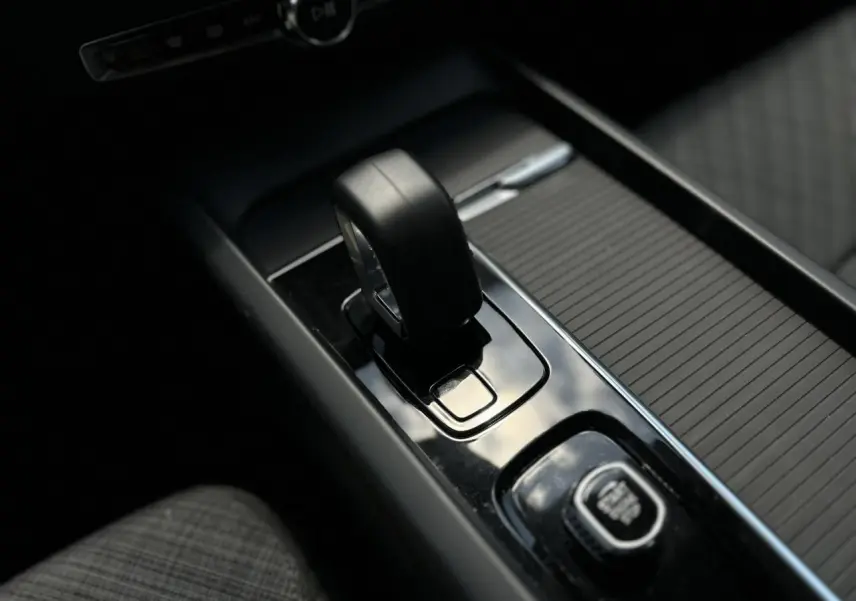 Gros plan sur le levier de vitesses noir et la commande Start/Stop dans la console centrale d'une Volvo S60 rouge Fusion 2024.